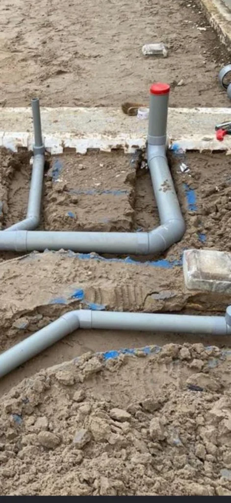 Nieuw aangelegde grijze rioleringsbuizen in uitgegraven grond